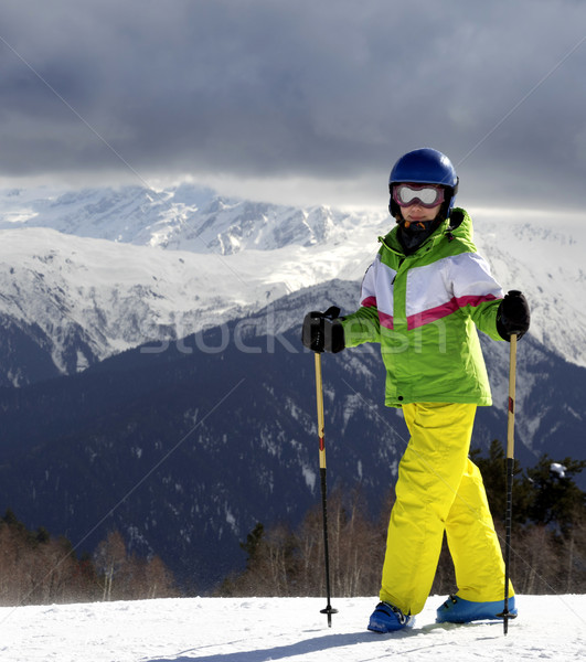 Young skier with ski poles at sun mountains and cloudy gray sky Stock photo © BSANI