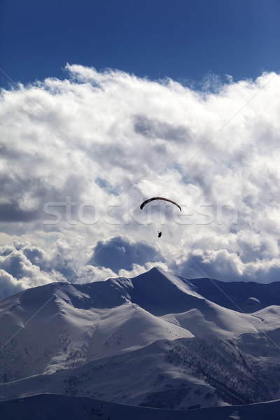 Winter mountains in evening and silhouette of paraglider Stock photo © BSANI