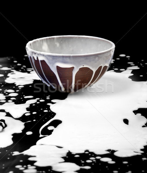Ceramic bowl and spilled milk in black Stock photo © BSANI