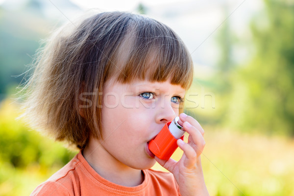 Stock photo: Little girl using inhaler on a sunny day