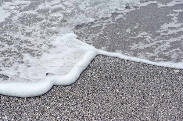Sea foam and pebbles in a beach Stock photo © byrdyak