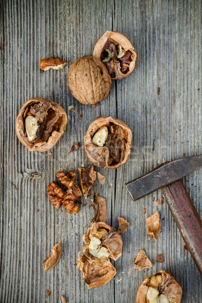 cracked walnuts and hammer on old wooden background Stock photo © c12