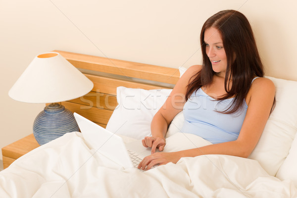 Stock photo: Beautiful woman working on computer in bed