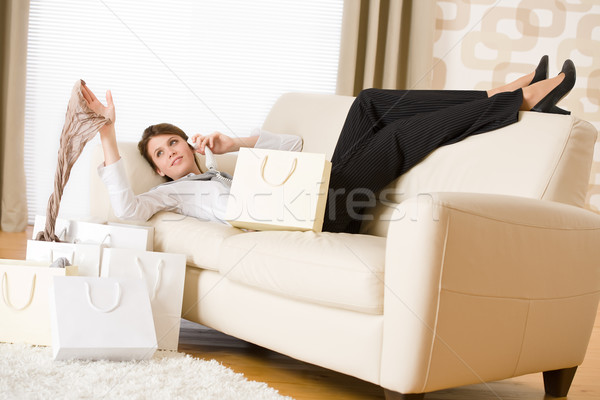 Young business woman lying down on sofa with shopping bag Stock photo © CandyboxPhoto
