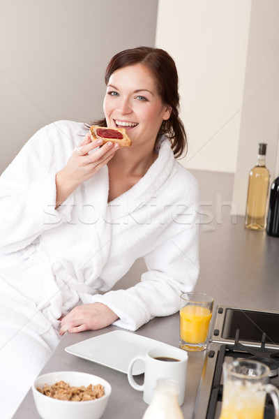 Stock photo: Young woman eating toast for breakfast in kitchen