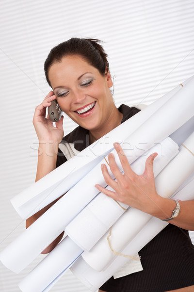 Stock photo: Young attractive female architect holding plans and telephone 