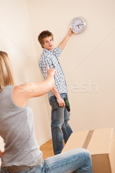 Moving house: Young couple hanging clock on wall Stock photo © CandyboxPhoto