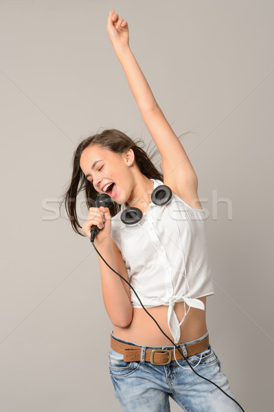 Stock photo: Teenage girl dancing singing with microphone
