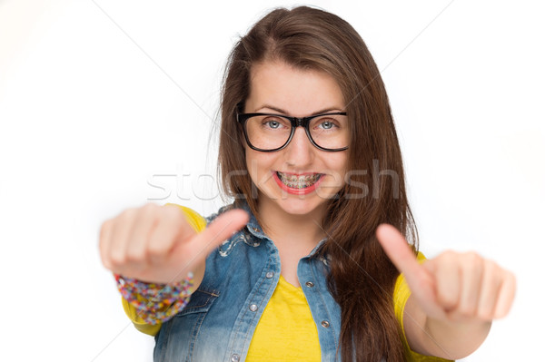 Girl in braces showing thumbs up isolated Stock photo © CandyboxPhoto