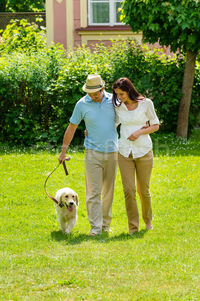 Happy couple walking dog on park lawn Stock photo © CandyboxPhoto