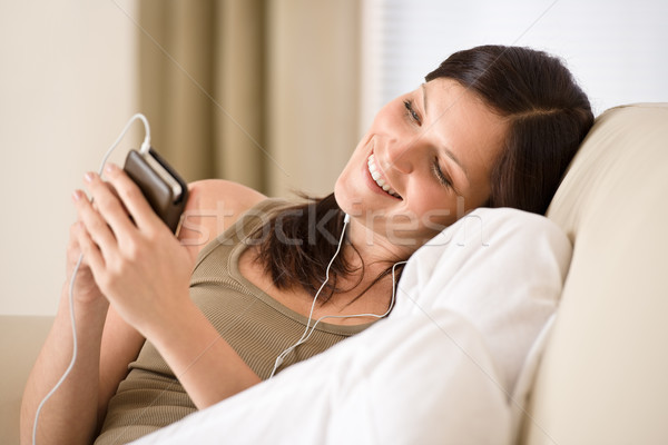 Woman holding music player listening with earbuds home Stock photo © CandyboxPhoto