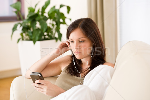 Woman holding music player listening with earbuds home Stock photo © CandyboxPhoto