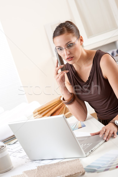 Stock photo: Young female designer on the phone at office with laptop