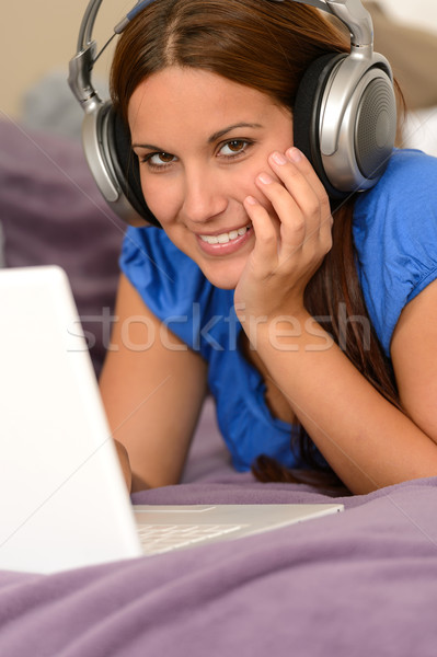 Stock photo: Young smiling girl using laptop with headphones