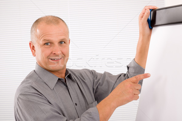 Mature businessman pointing at empty flip chart Stock photo © CandyboxPhoto