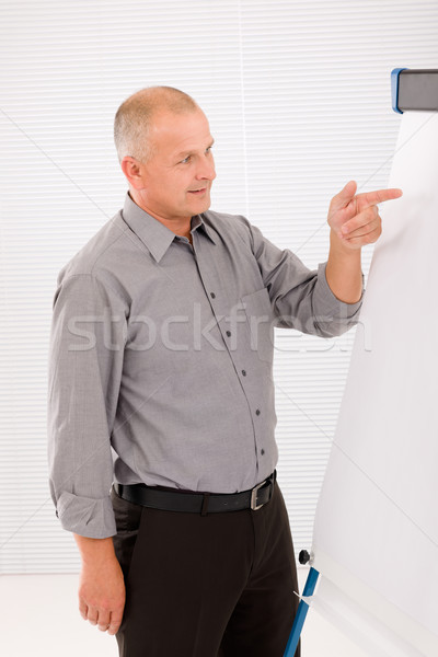 Mature businessman pointing at empty flip chart Stock photo © CandyboxPhoto