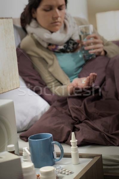 Stock photo: Ill woman in bedroom with flu pills