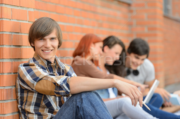 Stock foto: Studenten · Junge · Freunde · Sitzung · Backsteinmauer · lächelnd