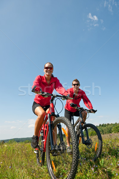 Young couple riding mountain bike in spring meadow Stock photo © CandyboxPhoto