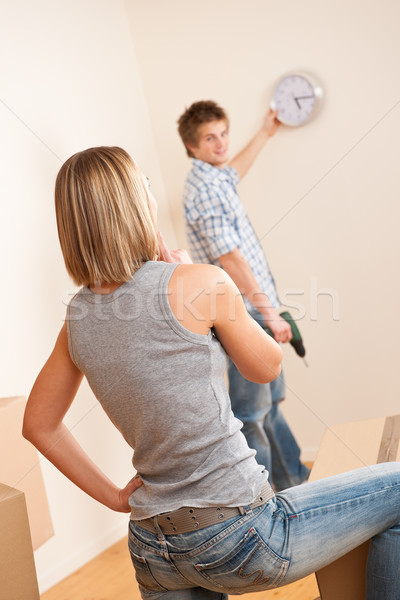 Moving house: Young couple hanging clock on wall Stock photo © CandyboxPhoto