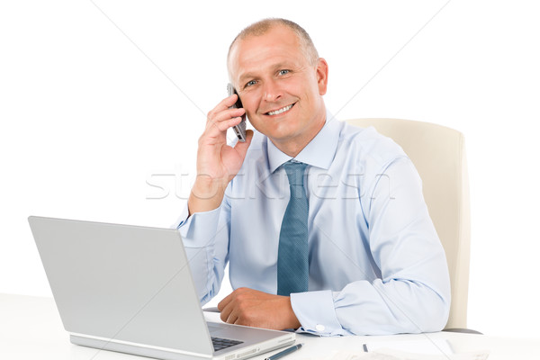 Stock photo: Smiling businessman sitting in office behind desk