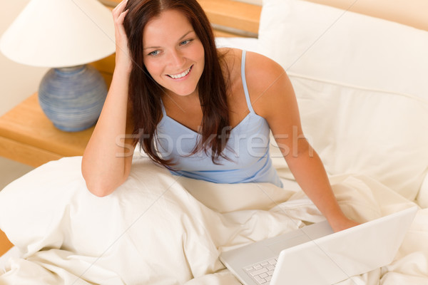Stock photo: Beautiful woman working on computer in bed