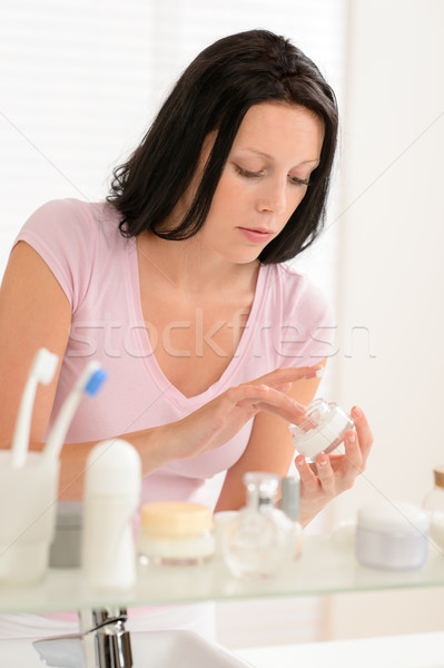Stock photo: Young woman put moisturizer cream in bathroom