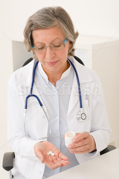 Stock photo: Medical doctor senior female hold pills office