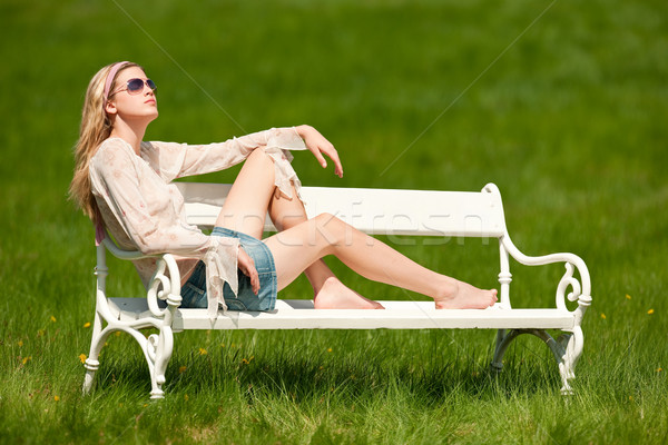 Stock photo: Spring - Young woman relaxing on bench in meadow