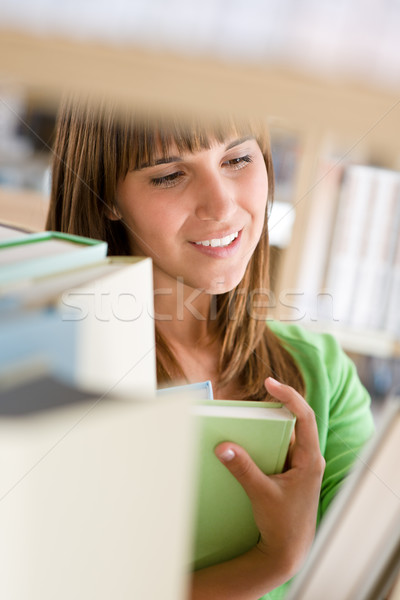 Stock photo: Student in library - cheerful woman stand by bookshelf