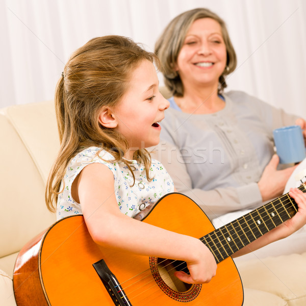 Stock photo: Young girl sing play guitar to grandmother