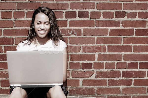 кирпичная стена ноутбука девушки довольно используя ноутбук Сток-фото © cardmaverick2