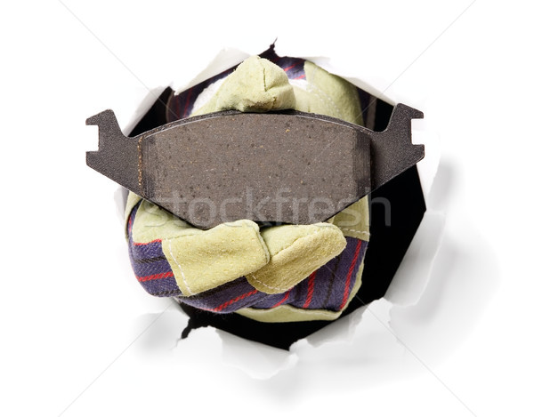 Stock photo: Man with gloves is holding brake pads in his finger through a hole