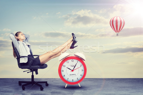Businesswoman sitting with her feet up on alarm-clock  Stock photo © cherezoff