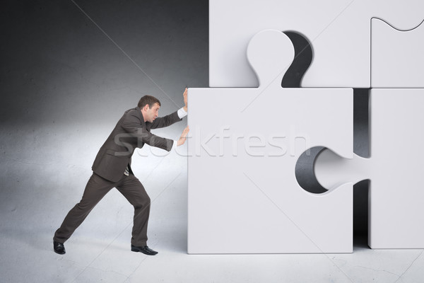 Businessman pushing puzzle piece Stock photo © cherezoff