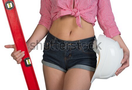 Nice sexy woman holding red building level and white helmet. In a cropped photo Stock photo © cherezoff