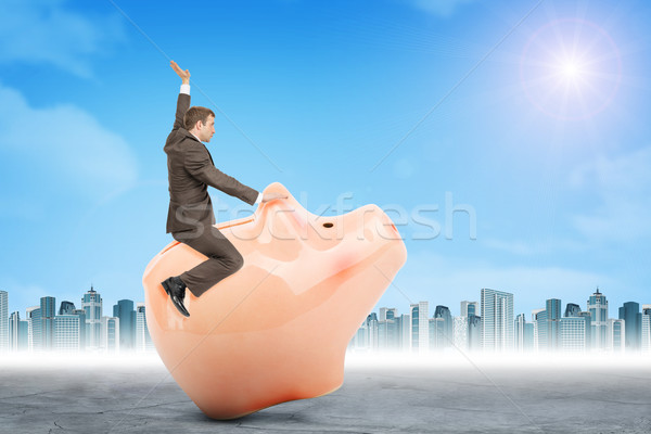 Businessman sitting on piggy bank, side view Stock photo © cherezoff