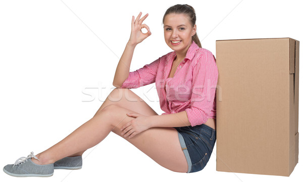 Woman sitting next to cardboard box, showing ok sign Stock photo © cherezoff