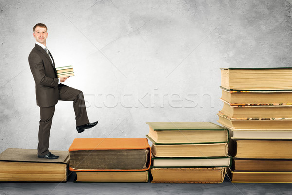 Businessman carries stack of books and walks up Stock photo © cherezoff
