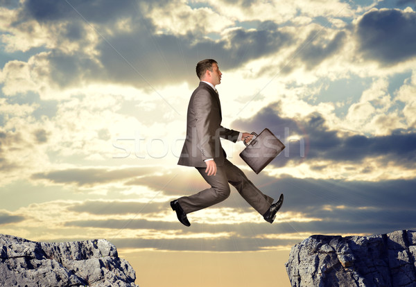 Businessman hopping over abyss Stock photo © cherezoff