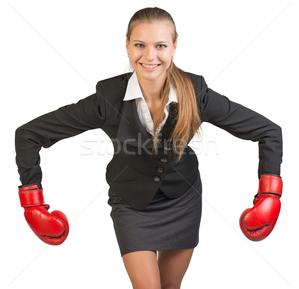 Stock photo: Businesswoman wearing boxing gloves bending forward with her arms bent and outstretched