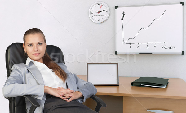 Businesswoman in office chair, with her hands clasped over stomach Stock photo © cherezoff