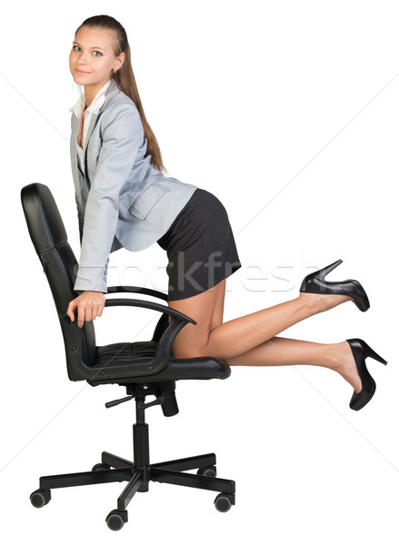 Businesswoman kneeling on office chair, looking at camera cheerfully Stock photo © cherezoff