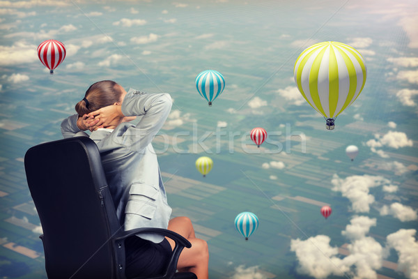 Businesswoman sitting with her hands clasped behind head against aerial view background Stock photo © cherezoff