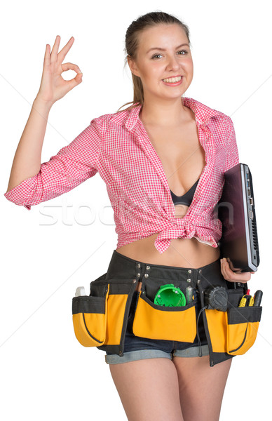 Woman in tool belt, with laptop under her armpit, showing okay sign Stock photo © cherezoff