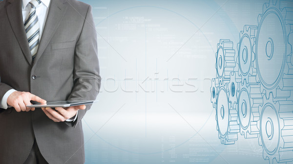 Businessman hold tablet pc. Gears and graphs Stock photo © cherezoff