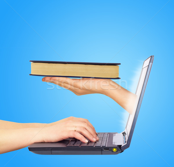 Book in hand from monitor screen. Hands typing on keyboard Stock photo © cherezoff