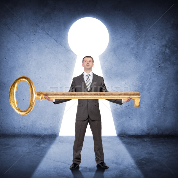 Man in suit holding huge gold key Stock photo © cherezoff