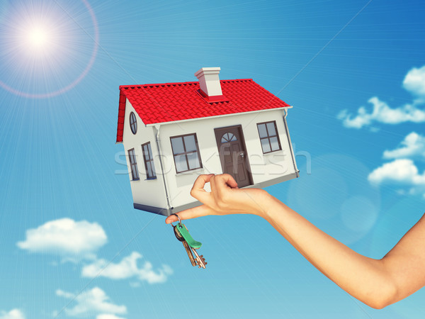 White house and keys in hand with red roof, brown door, chimney. Background sun shines brightly Stock photo © cherezoff