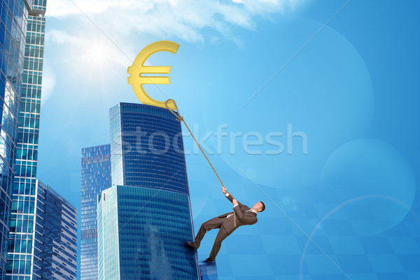 Businessman climbing skyscraper with euro sign Stock photo © cherezoff